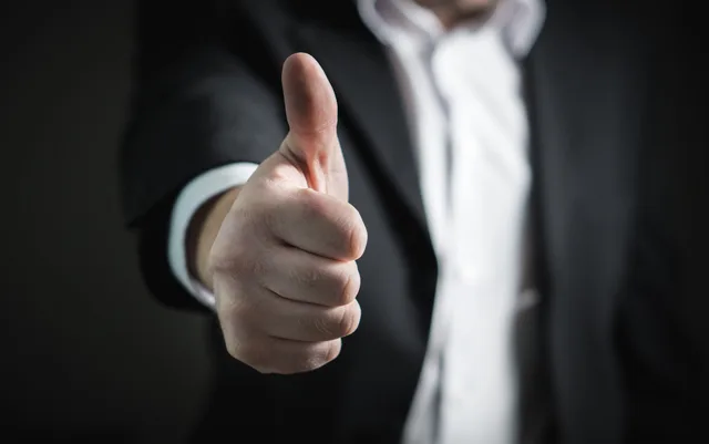 A close-up of a man's thumbs up gesture, symbolizing success and agreement. B2B influencer marketing team roles that protect delivery