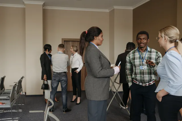 Professionals engaging in conversation at a diverse business conference with corporate attire indoors. How to build a UK business-to-business influencer longlist in six steps